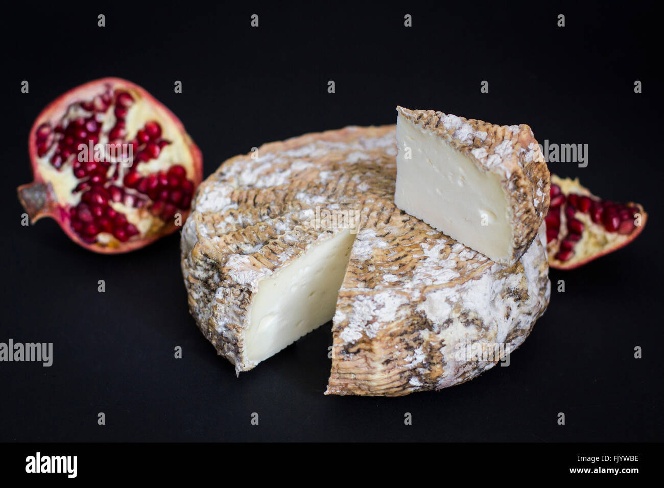 Di età compresa tra i formaggi di capra con melagrane su sfondo nero Foto Stock