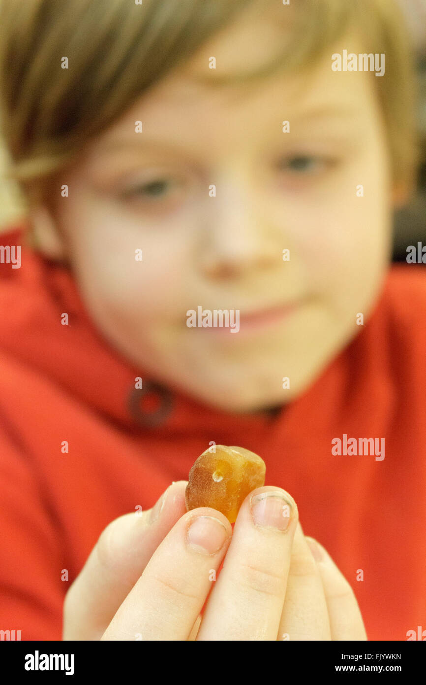 Ragazzo giovane tenendo in mano un pezzo di ambra in mano Foto Stock