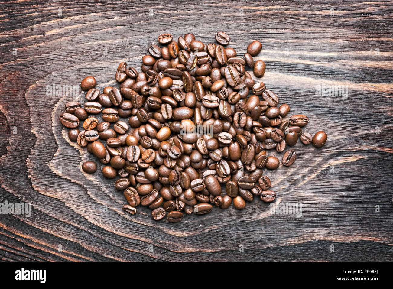 Pila di chicchi di caffè su sfondo di legno Foto Stock