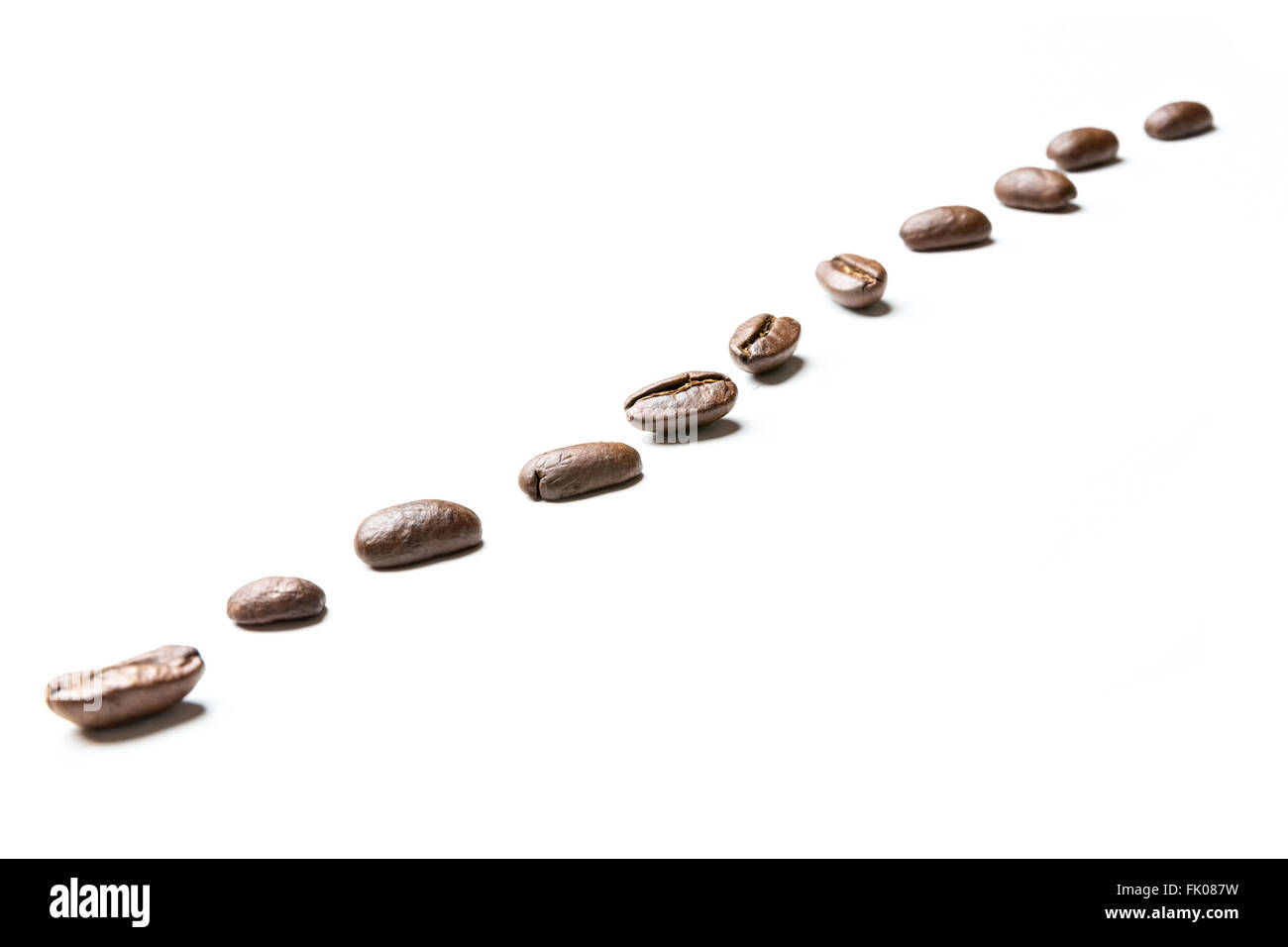 I chicchi di caffè in una riga isolata su sfondo bianco Foto Stock