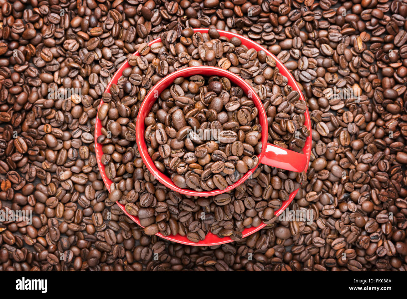 Red tazza riempita con i chicchi di caffè su sfondo di legno Foto Stock