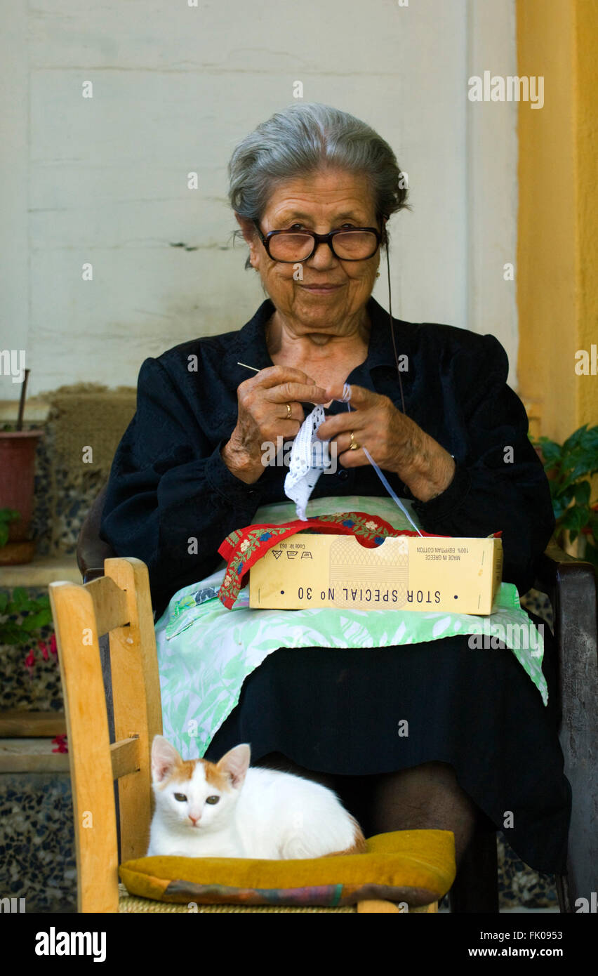 Griechenland, Kreta, Archanes, alte Frau sitzt auf Stuhl und stickt Foto Stock