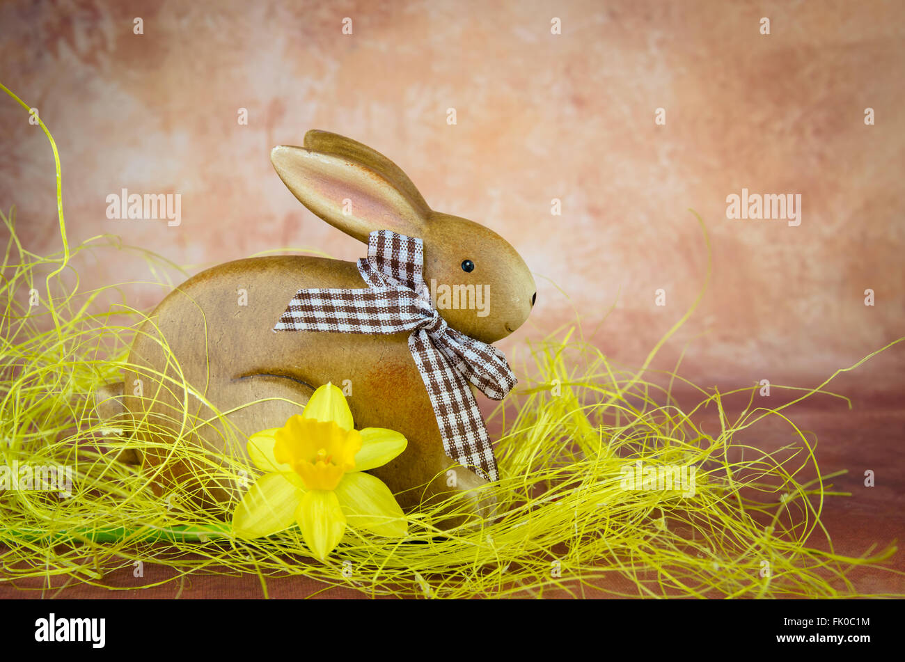 Brown coniglietto di Pasqua e daffodil decorazione contro il marrone scuro dello sfondo Foto Stock