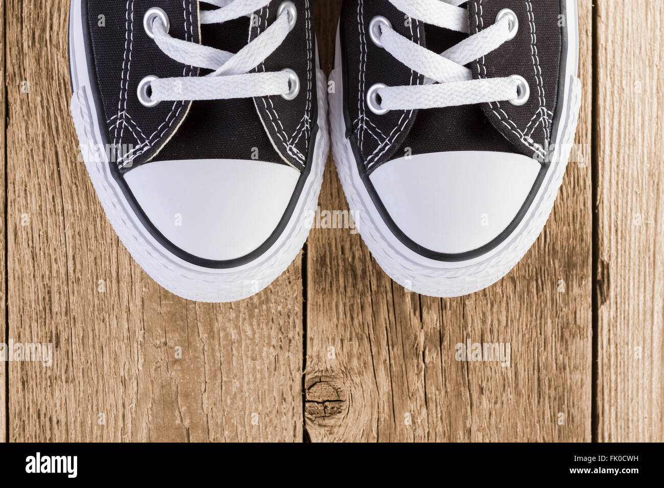Sneakers nero scarpe su sfondo di legno. Foto Stock
