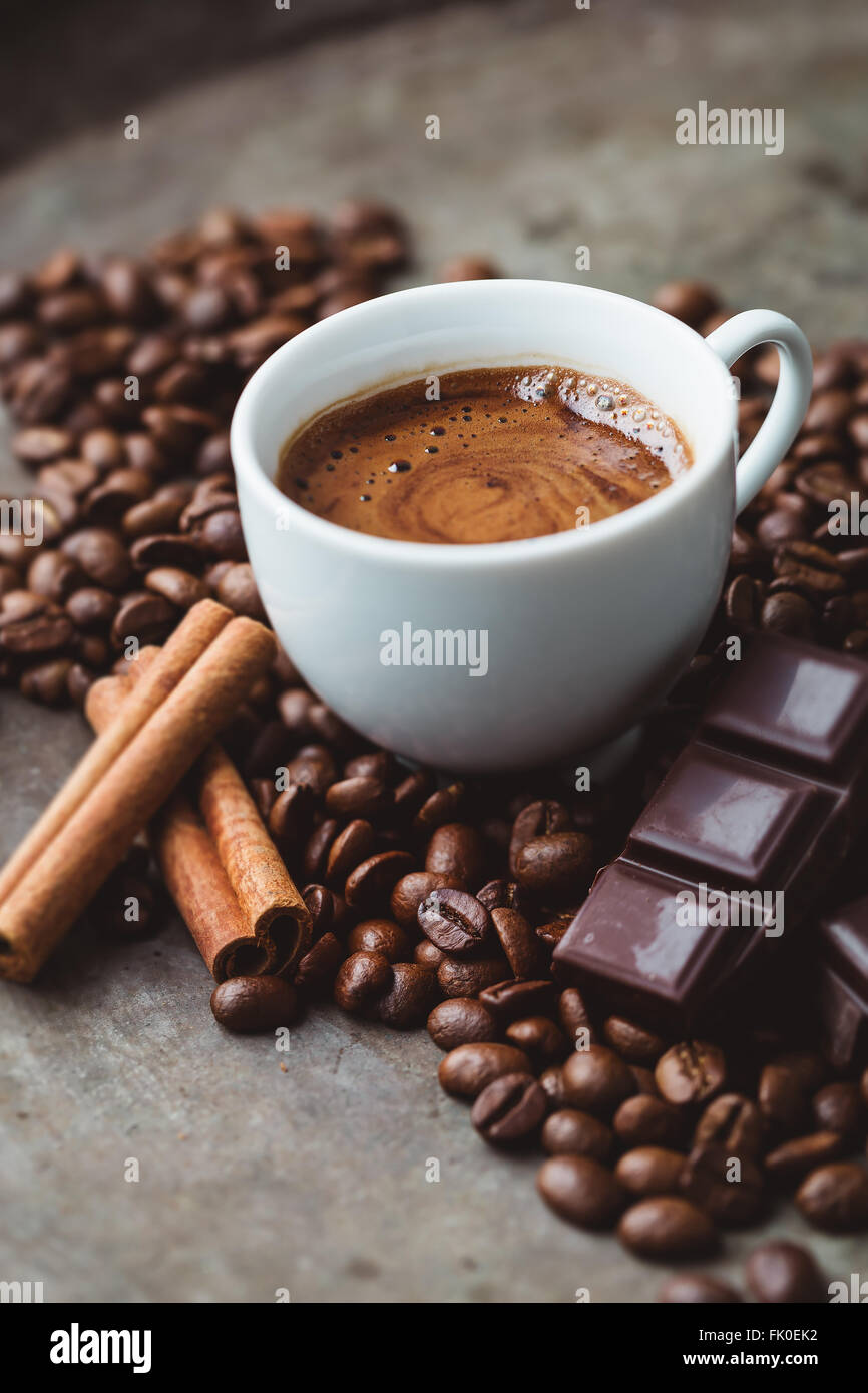 Tazza di caffè circondato da cioccolato, bastoncini di cannella e i chicchi di caffè Foto Stock