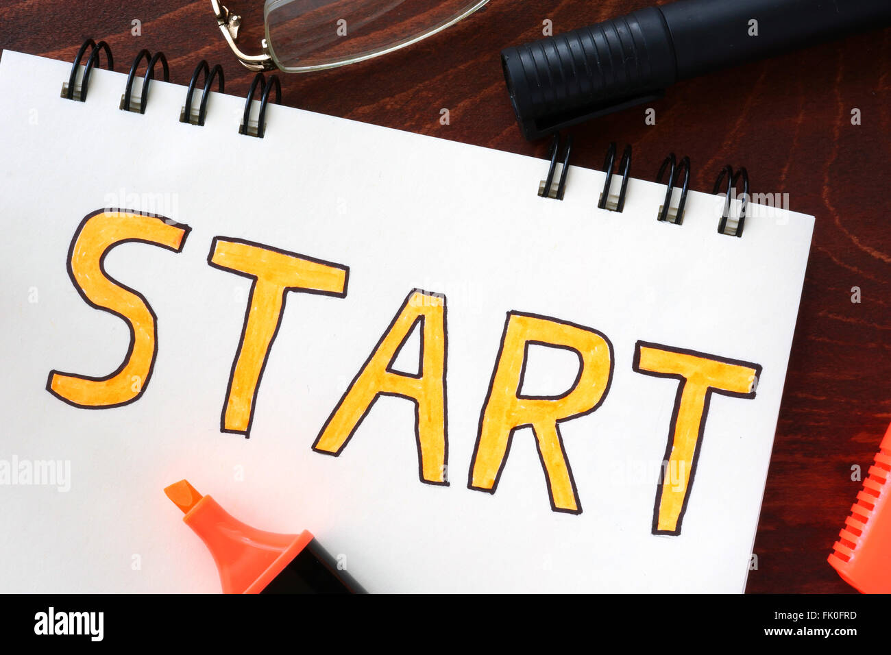 Concetto di inizio scritto in un notebook su un tavolo di legno. Foto Stock