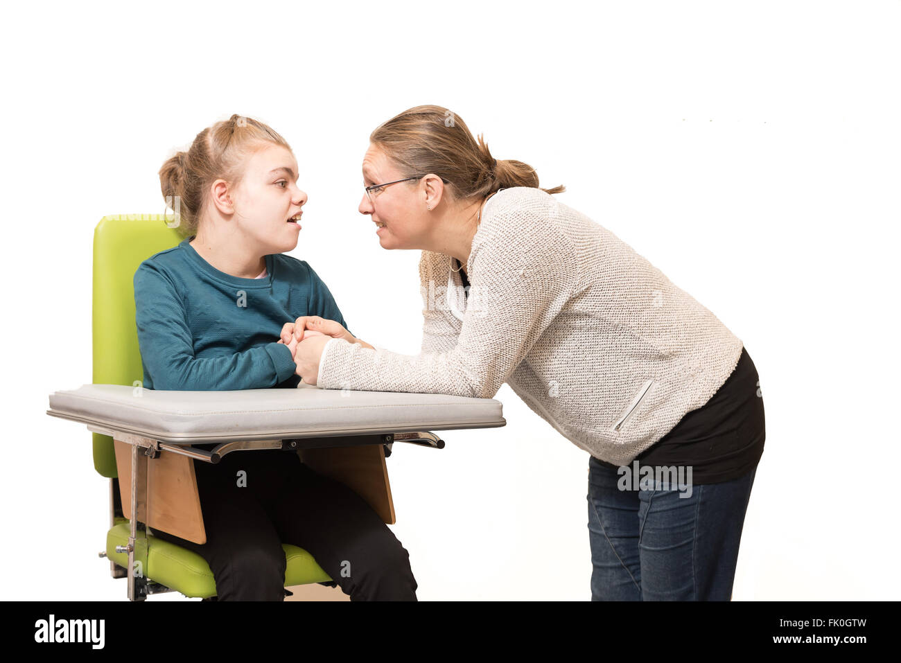 Un bambino disabile su sedia a rotelle essendo curata da un mental health care assistant Foto Stock