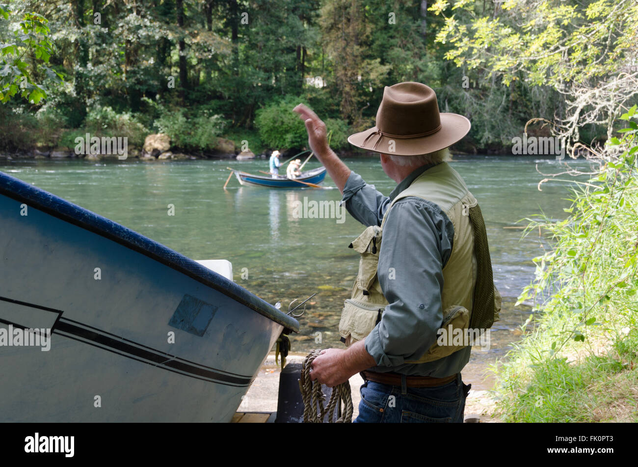 Un uomo onde agli altri pescatori in un fiume Mckenzie barca deriva. Il fondo piatto design senza chiglia è stata sviluppata per naviga Foto Stock