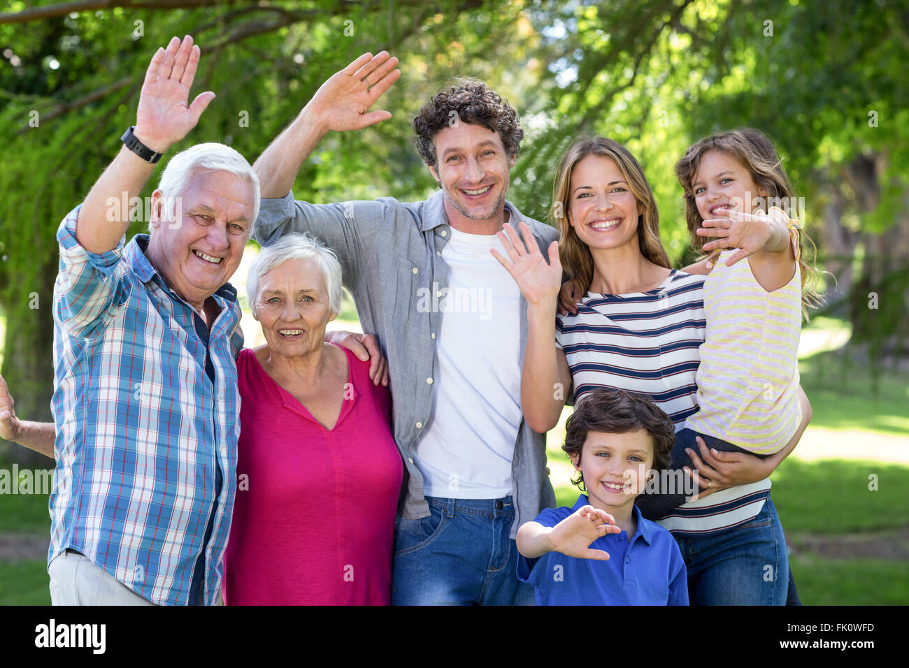Famiglia sorridente sventolare le mani Foto Stock
