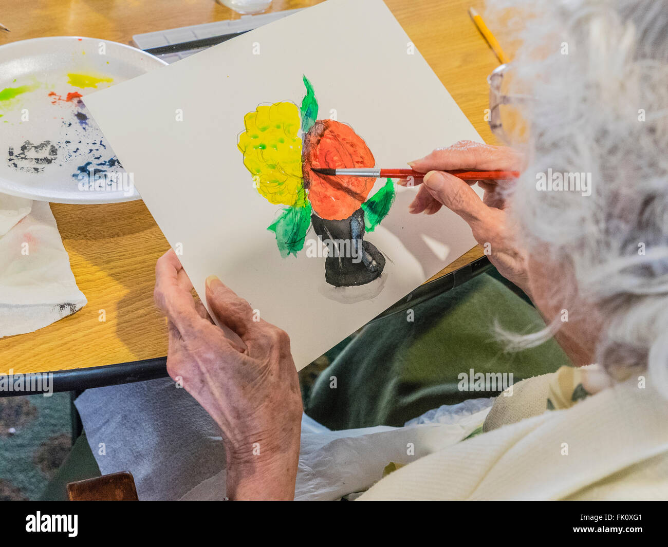 Una femmina senior citizen vernici in un acquerello di classe per gli anziani al Garden Court senior residence a Santa Barbara, California. Foto Stock