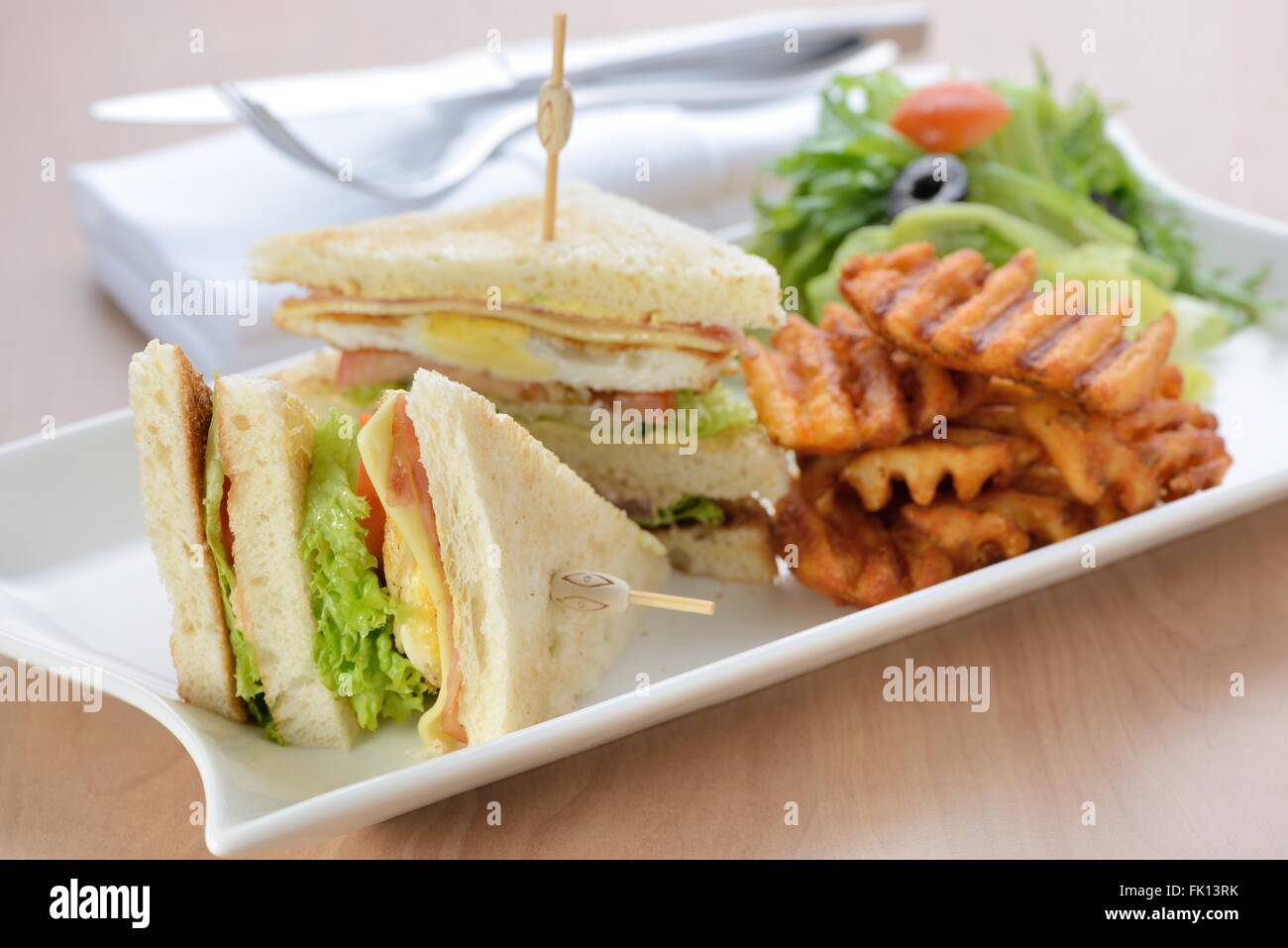 Appena sfornati club sandwich servito con patate fritte Foto Stock