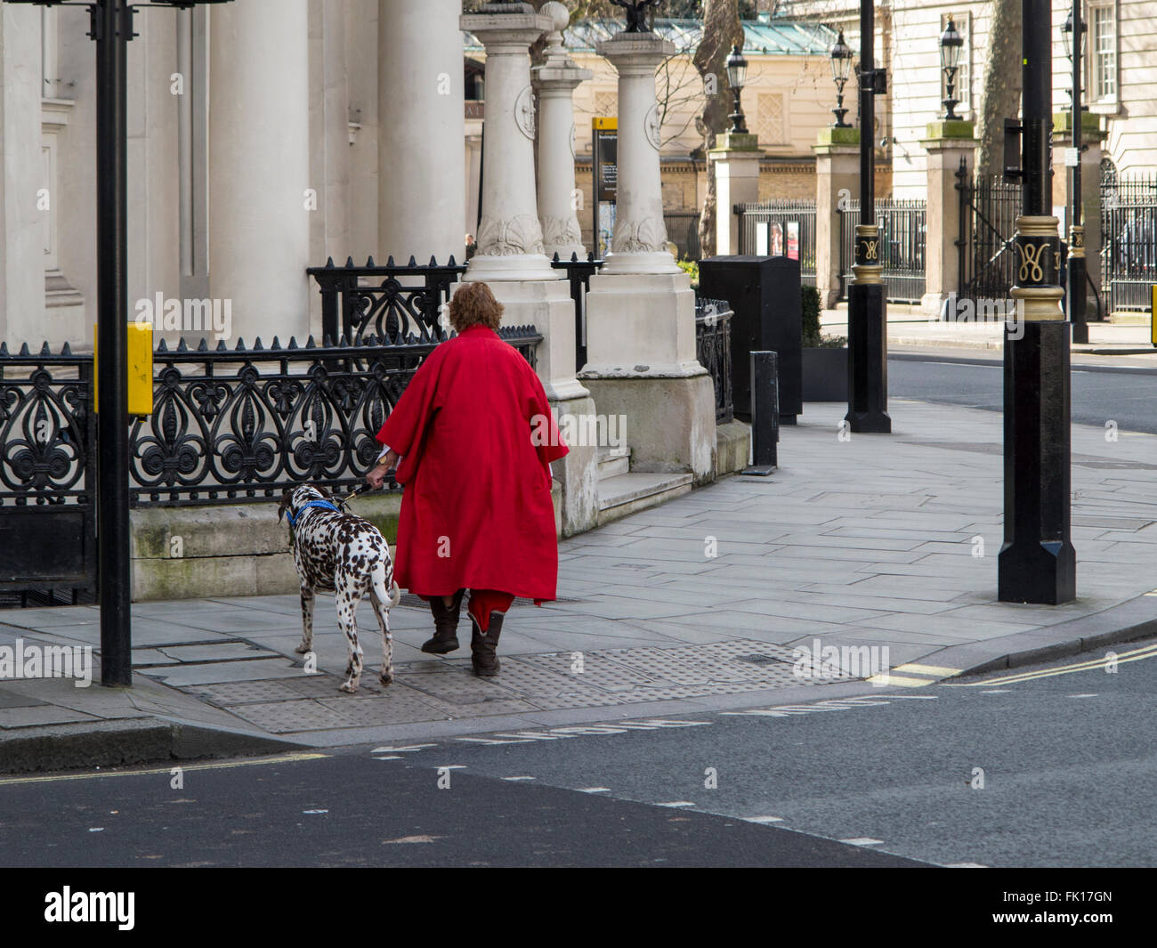 Una donna in un rivestimento di colore rosso con un cane dalmata in centro a Londra Foto Stock