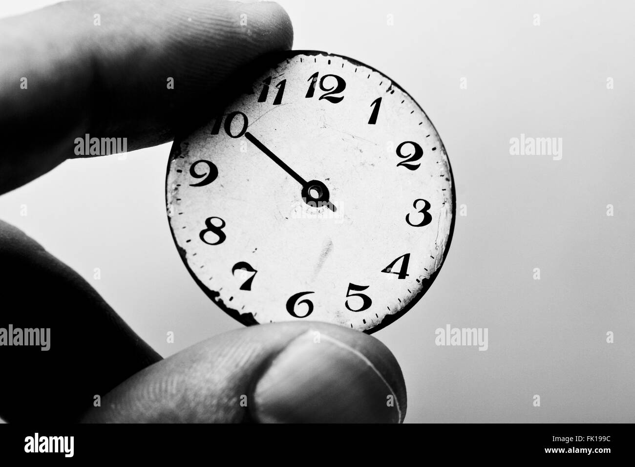 Immagine in bianco e nero di due dita tenendo un quadrante di orologio Foto Stock