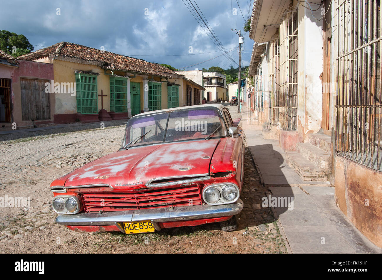 Classico vecchio rosso americano auto parcheggiate su strade a ciottoli della città coloniale di Trinidad, Cuba Foto Stock