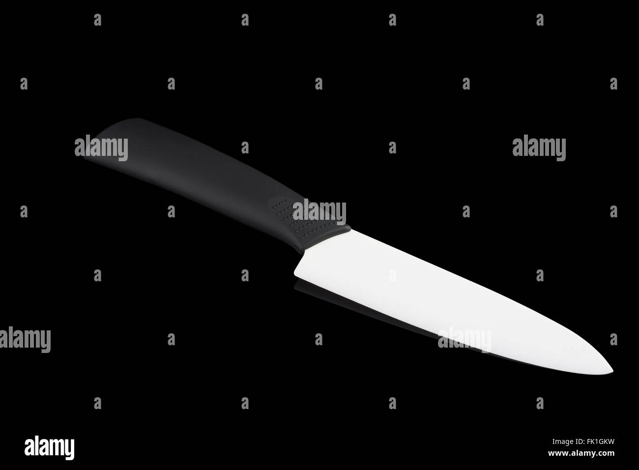 Un bianco di ceramica coltello nero su sfondo riflettente Foto Stock