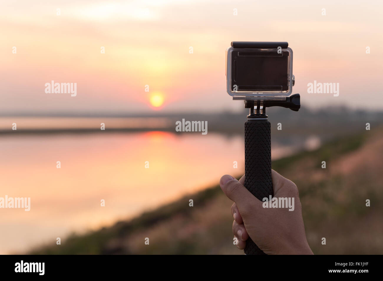 Mano azienda extreme fotocamera per scattare foto durante il tramonto Foto Stock