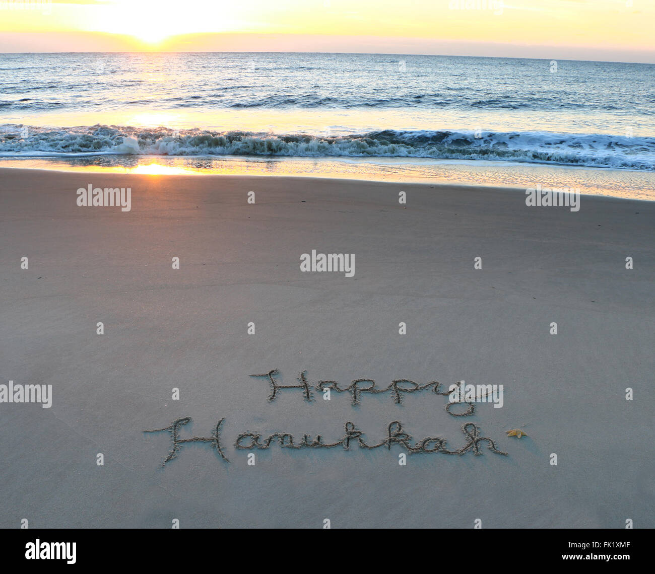 Happy Hanukkah scritto nella sabbia sulla spiaggia Foto Stock