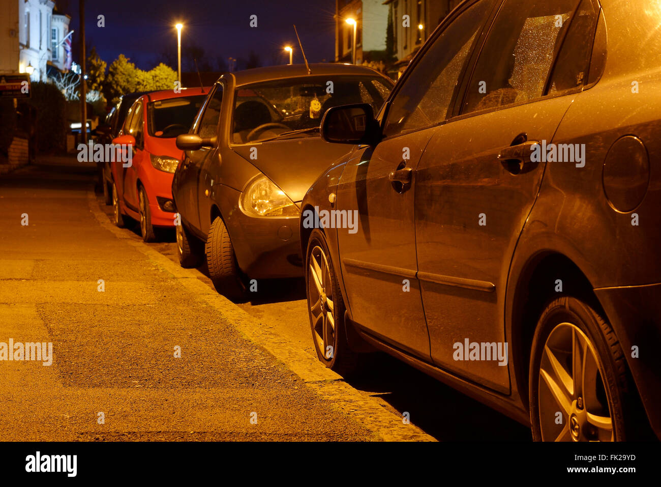 Auto parcheggiate sul lato di una strada di notte Foto Stock
