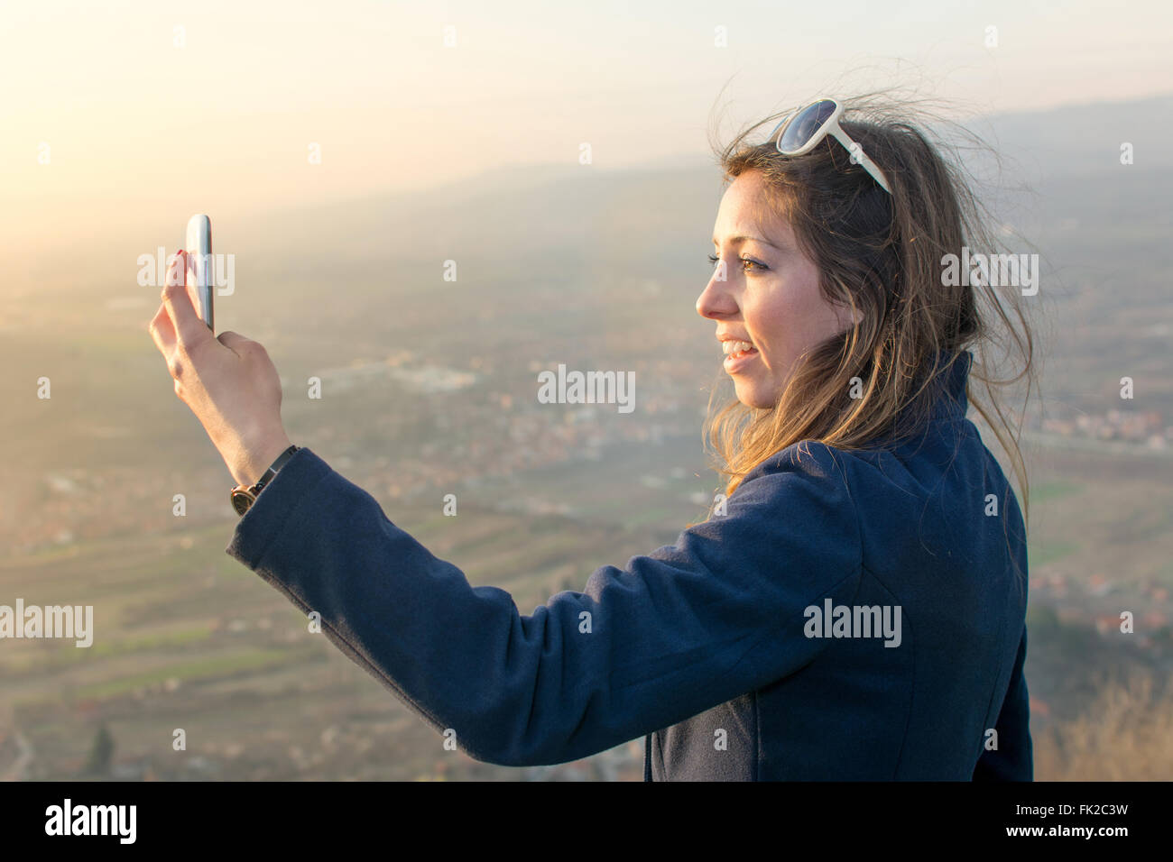 Ragazza tenendo un selfie su una escursione al tramonto Foto Stock