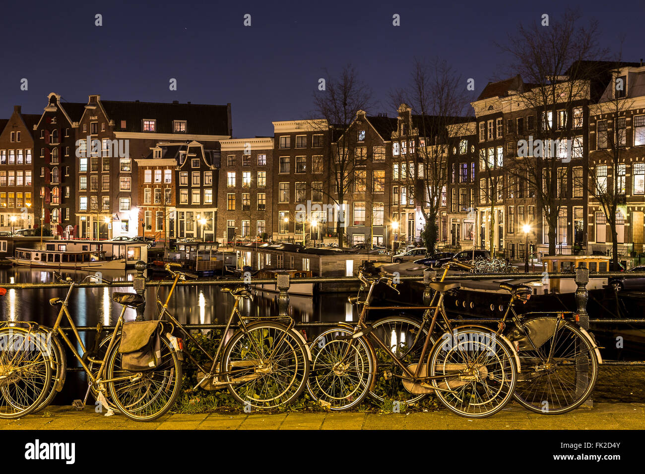 Una vista lungo il canale Waalseilandgracht ad Amsterdam di notte con la bici come il fuoco principale in primo piano. Foto Stock