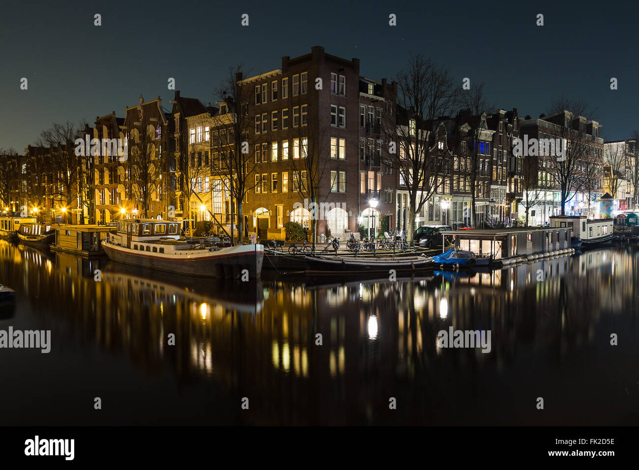 Una vista di edifici e barche lungo i canali di Amsterdam di notte. Riflessioni può essere visto nell'acqua. Non vi è lo spazio per la copia Foto Stock