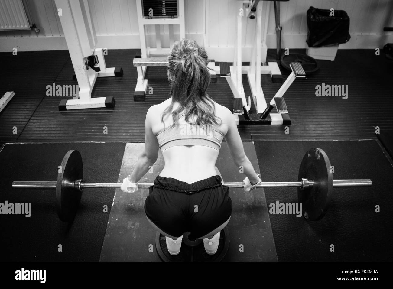 Giovane e bella femmina concorrente fitness su un SQUAT RACK Foto Stock