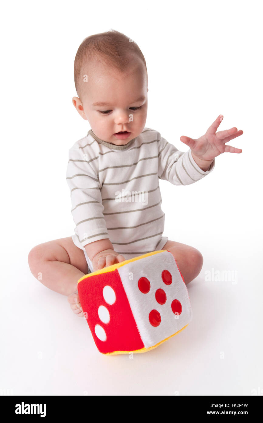 Bambino gioca con un morbido giocattolo di dadi su sfondo bianco su sfondo bianco Foto Stock