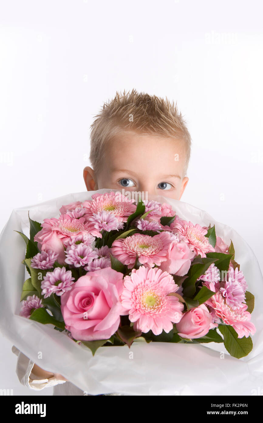 Little Boy è nascosto dietro un mazzo di fiori su sfondo bianco Foto Stock