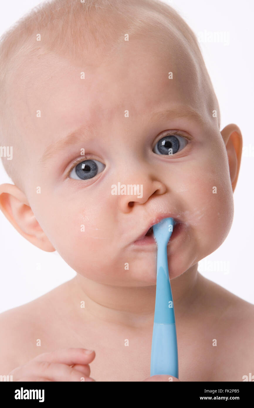 Baby Boy sta spazzolando i suoi denti con uno spazzolino da denti su sfondo bianco Foto Stock
