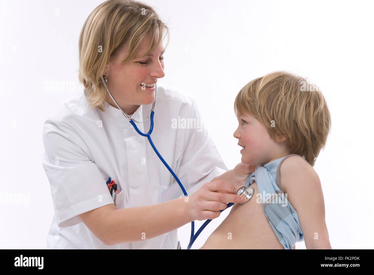 Medico donna sta ascoltando il ritmo cardiaco di un ragazzino con uno stetoscopio su sfondo bianco Foto Stock