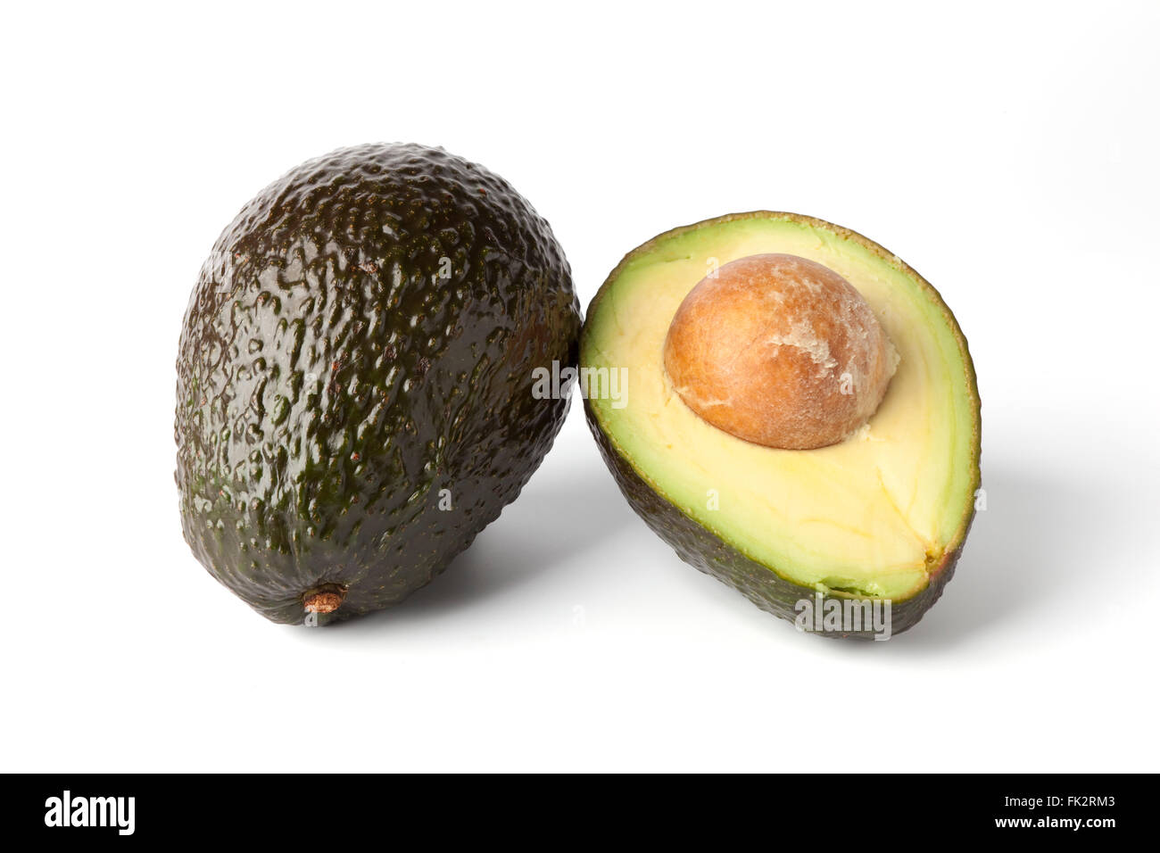 Intero e una metà di avocado fresco su sfondo bianco Foto Stock