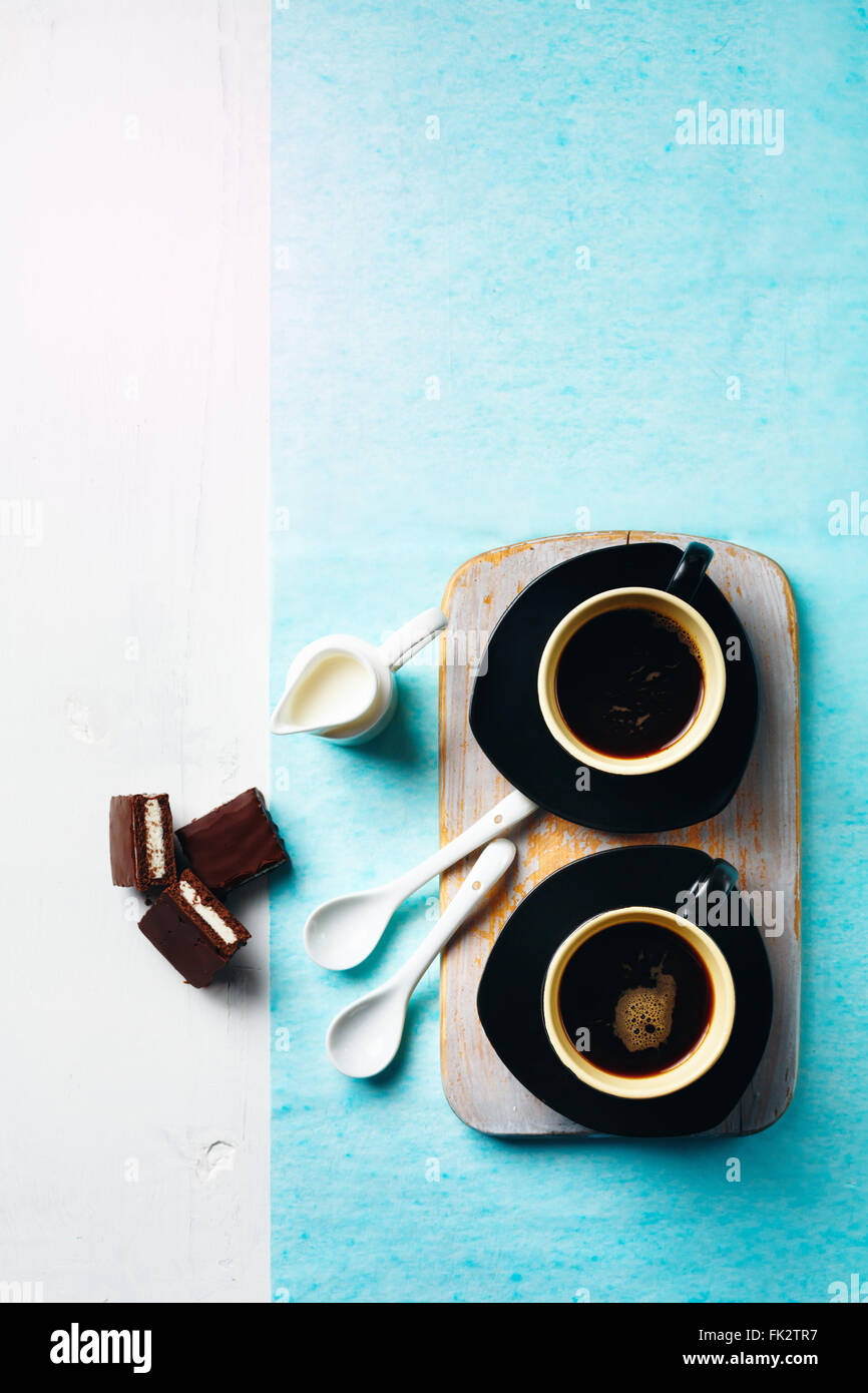 Caffè del mattino tavola. Due tazze di caffè con torta al cioccolato e bricco per il latte. Messa a fuoco selettiva, vista dall'alto. Foto Stock