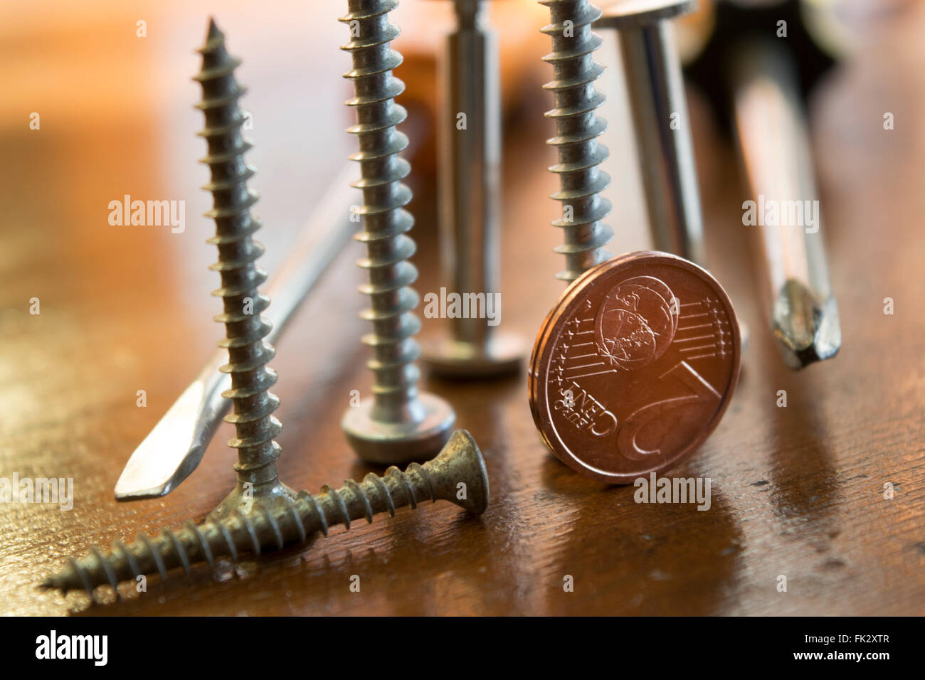 Viti bulloni e due cento per simboleggiare il concetto di lavoro manuale , professioni e profitti monetaria Foto Stock