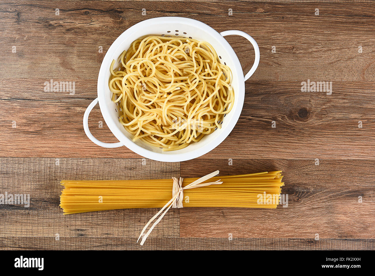 Vista aerea del cotto e spaghetti secchi. La pasta cotta è in uno scolapasta e le materie prime è legata con rafia. Orizzontale su un Foto Stock