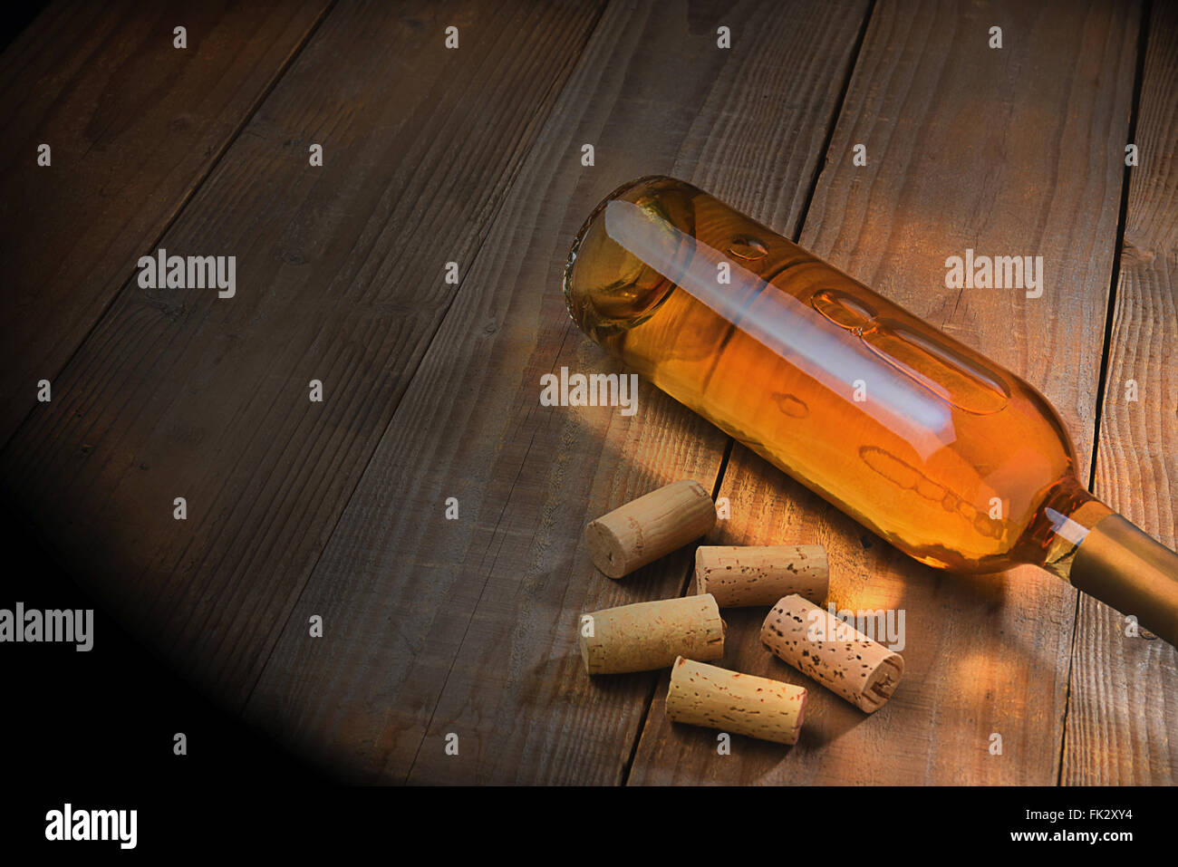 Vista superiore di una bottiglia di vino la posa su una tavola di legno con forte calda luce laterale. Foto Stock