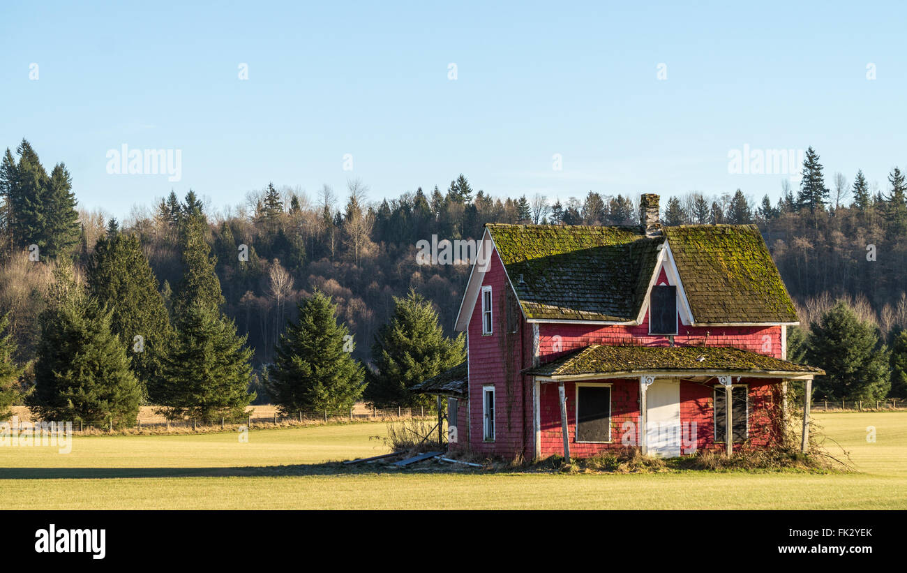 Vecchio rosso fatiscente casa colorata in un campo in Fraser Valley della Columbia britannica in Canada Occidentale Foto Stock