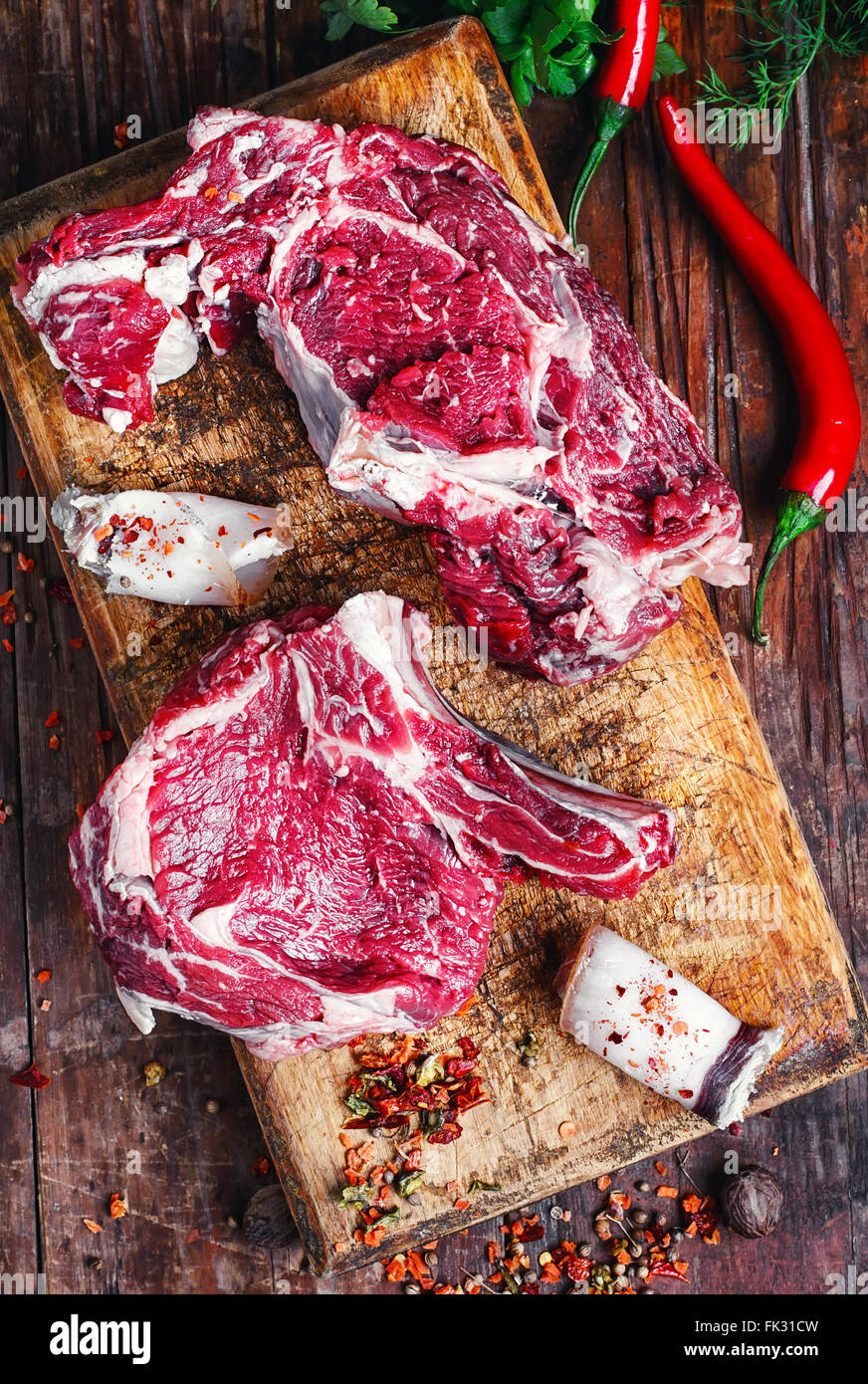 Un trito di pezzi di carne di manzo crudo con spezie sul tagliere di legno Foto Stock
