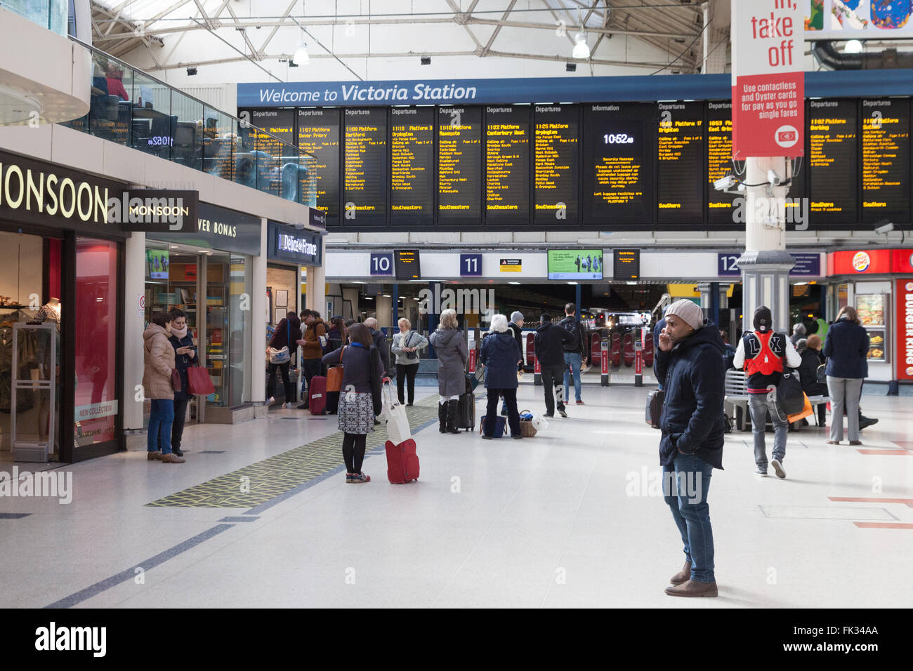 Victoria Station London - persone nell'atrio che guardano il bordo di partenza; Victoria Train Station, London UK Foto Stock