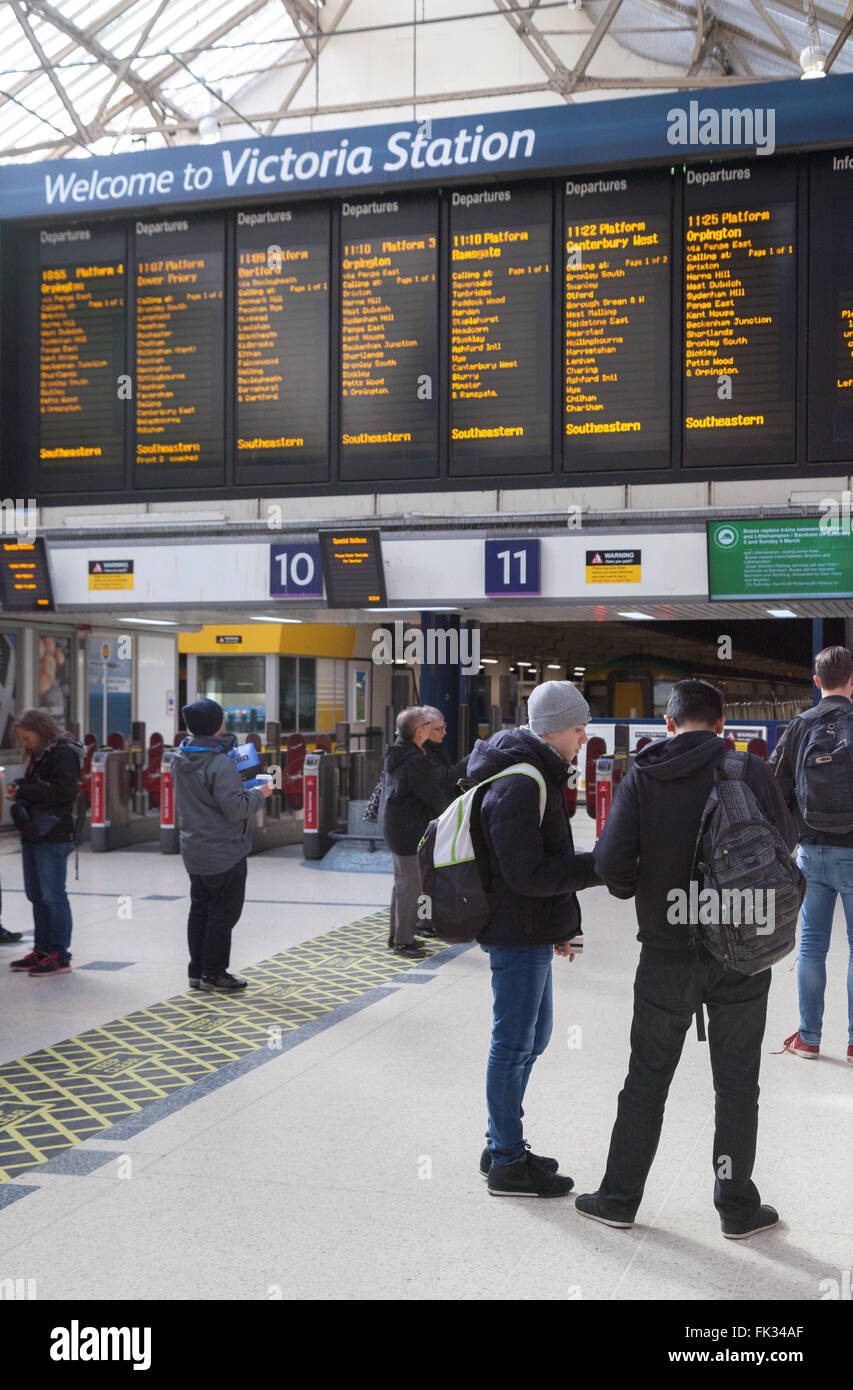 Victoria Station London - persone nell'atrio che guardano il bordo di partenza; Victoria train station, London UK Foto Stock