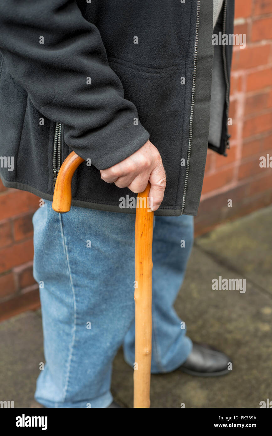 Uomo anziano tenendo un bastone da passeggio Foto Stock