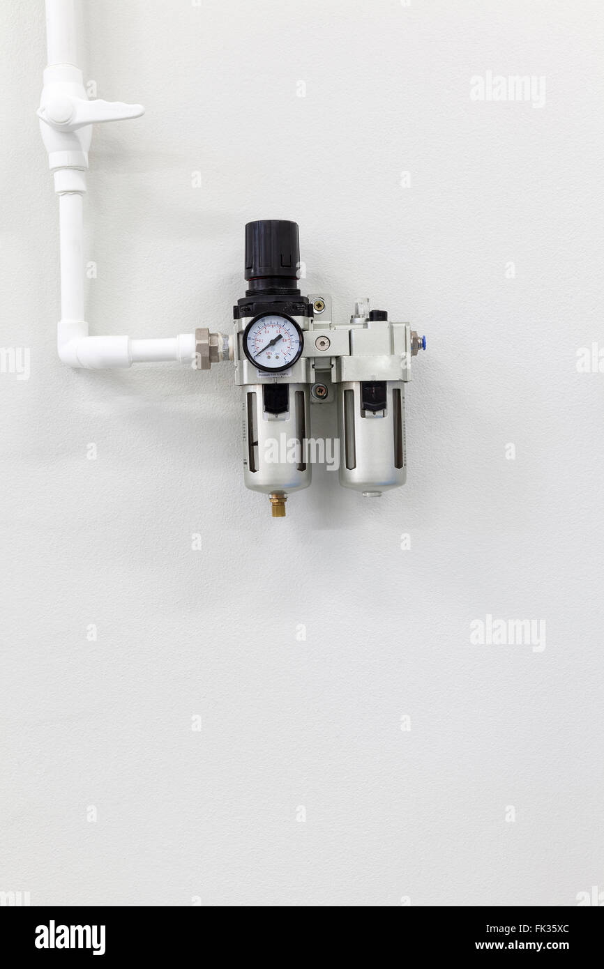 Regolatore di pressione con un manometro sul muro bianco Foto Stock