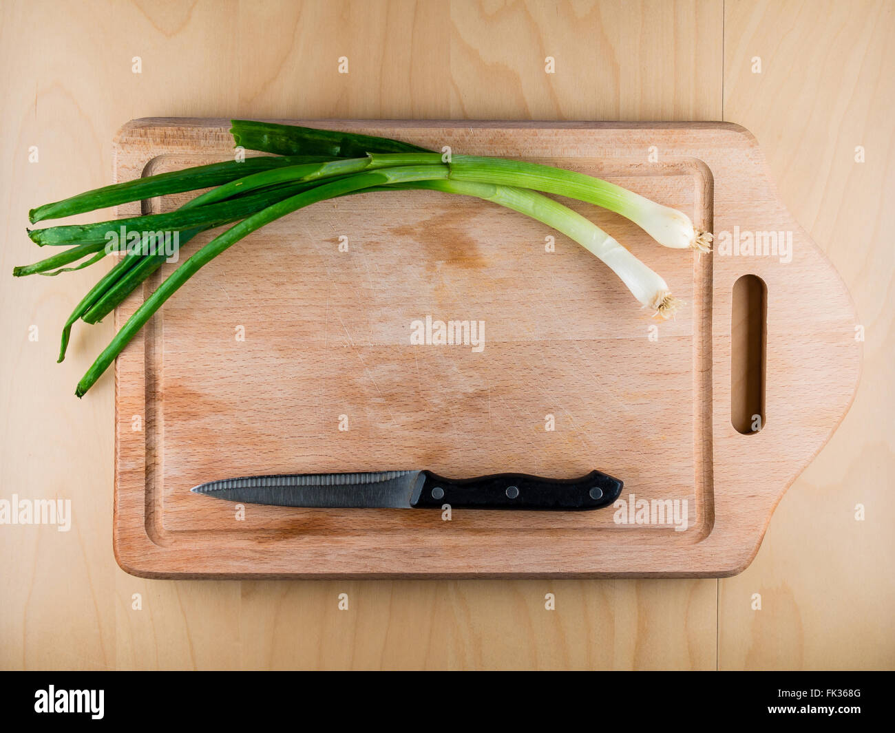 Mazzetto cipolla sul tagliere in legno con coltello, copyspace Foto Stock