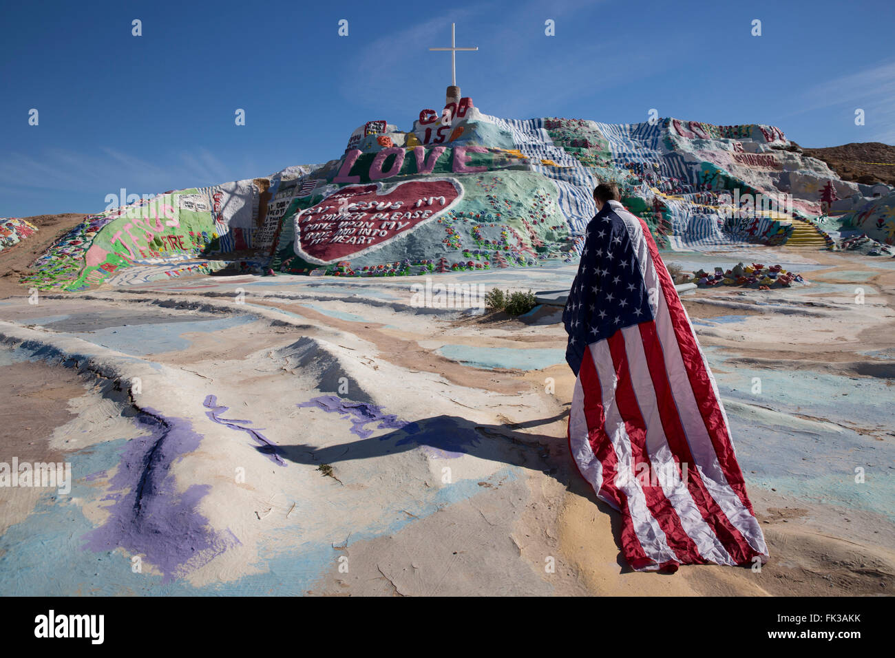 Giovane uomo drappeggiati in bandiera americana, salvezza montagna, Niland, CALIFORNIA, STATI UNITI D'AMERICA Foto Stock
