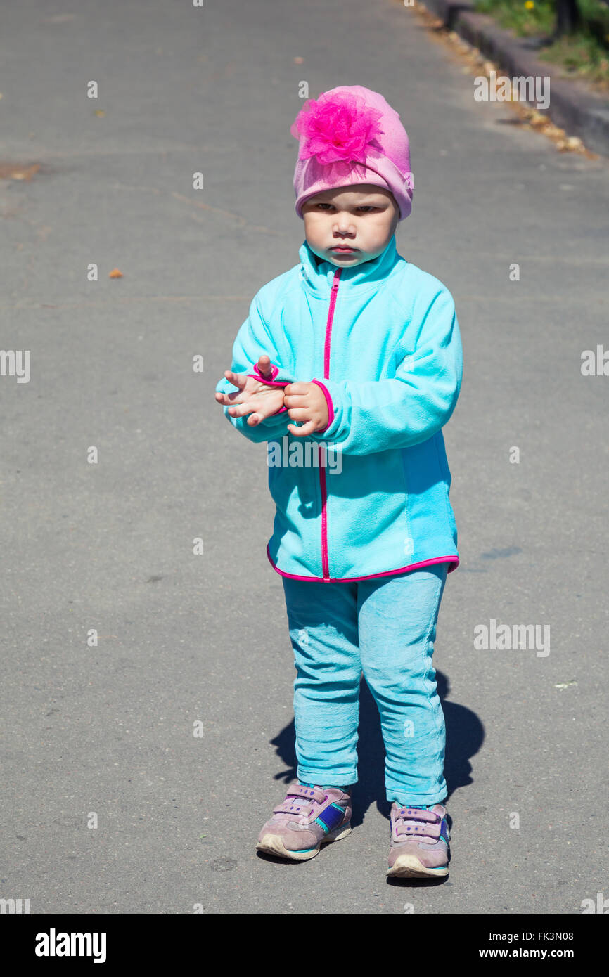 Ritratto all'aperto in piena crescita della piccola bambina in piedi su un asfalto urbano road Foto Stock