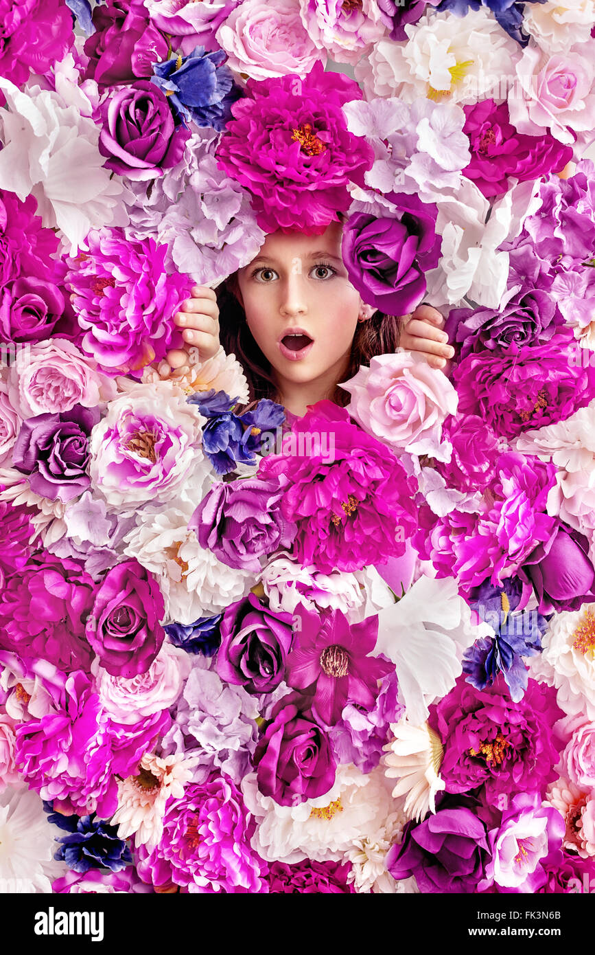 Sorpreso bambina dietro un muro di fiori Foto Stock