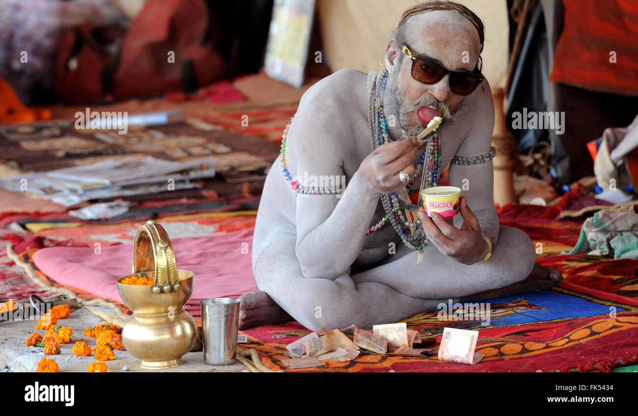 Una bizzarra immagine di un Naga Sadhu in Maha Kumbh avente ice cream , di Allahabad, Uttar Pradesh, India Foto Stock