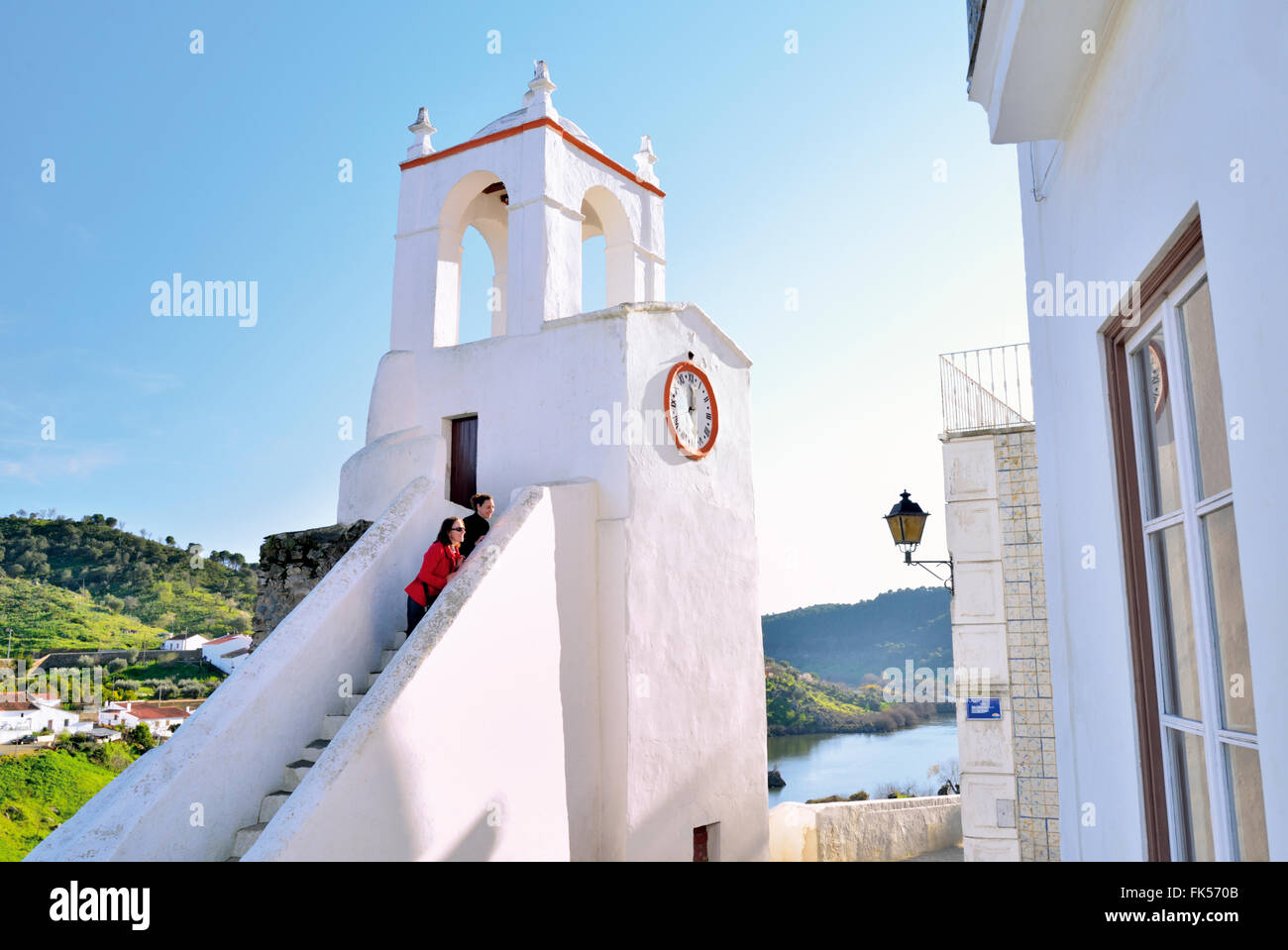 Portogallo Alentejo: due donne guardando da le fasi della storica torre dell'orologio di Mértola presso il fiume Guadiana Foto Stock