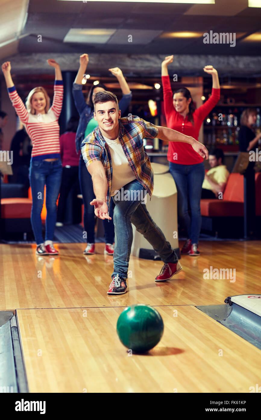 Felice giovane uomo gettando la sfera in bowling club Foto Stock