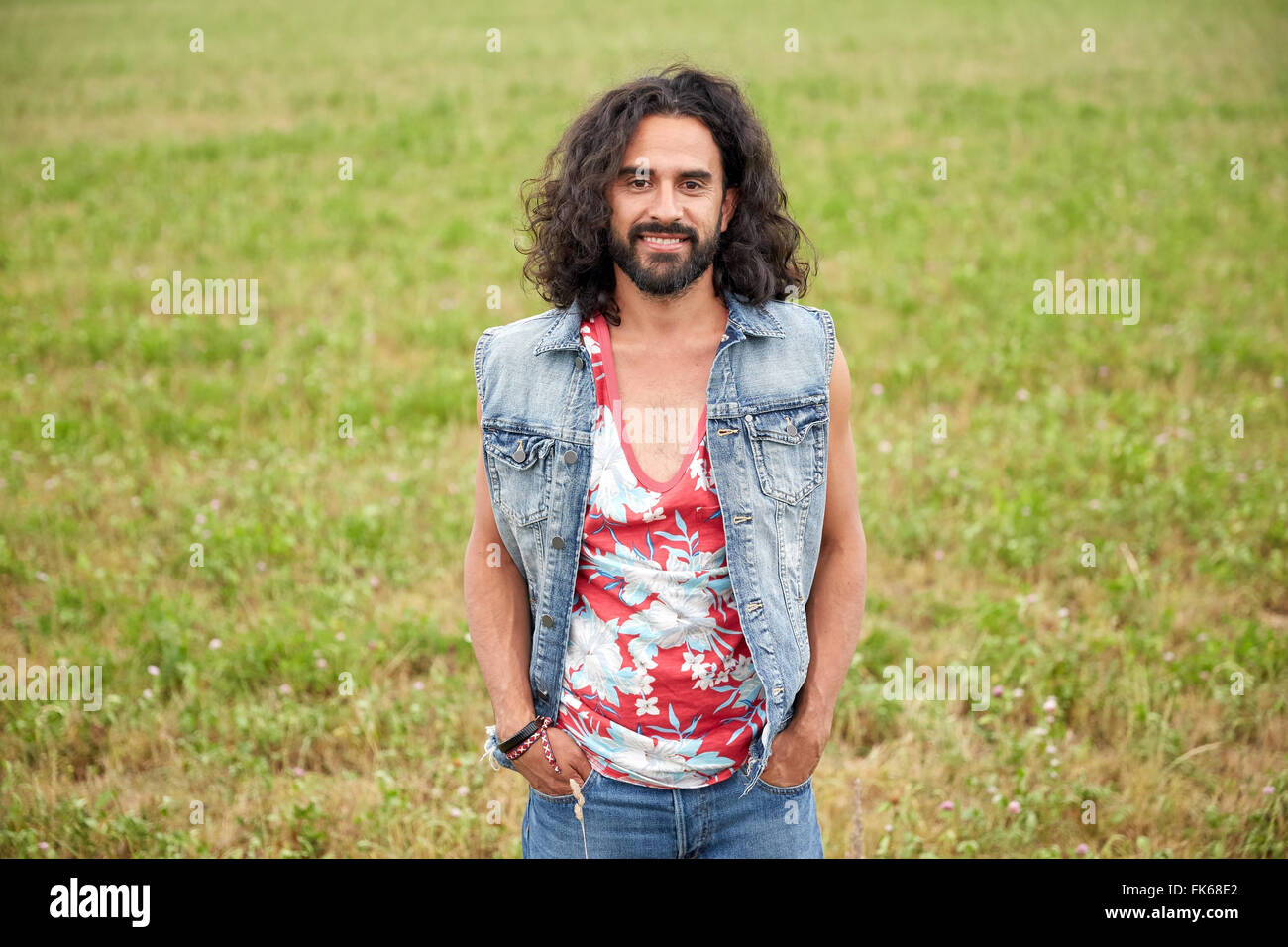 Sorridente giovane uomo hippie sul campo verde Foto Stock