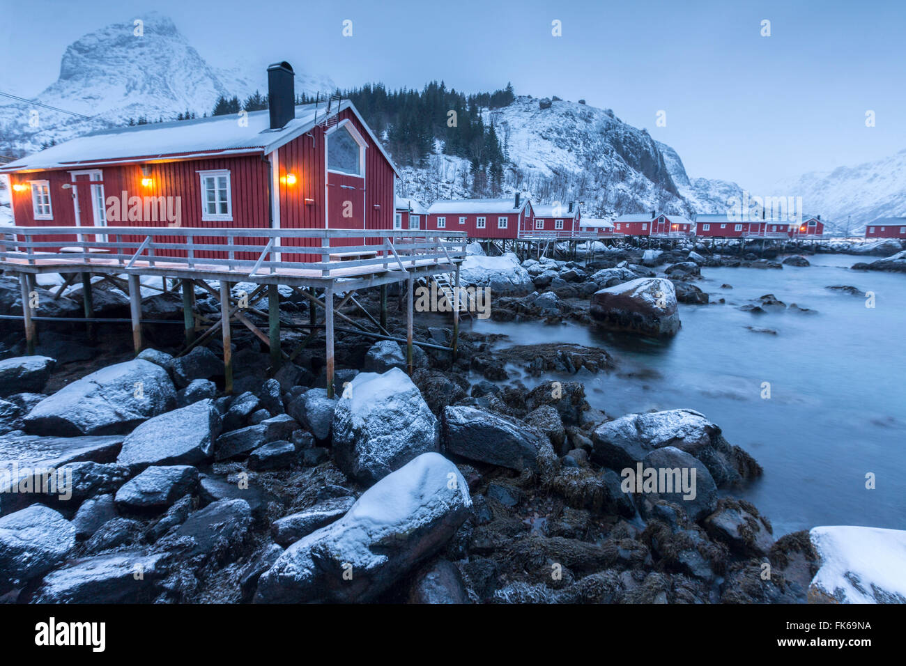 Tipiche case di pescatori chiamato rorbu nel paesaggio innevato al crepuscolo, Nusfjord, Nordland County, Isole Lofoten in Norvegia Foto Stock